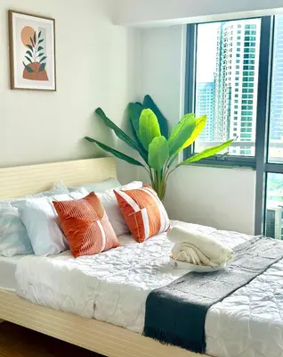 a bedroom with a bed with pillows and a plant at 1BR Acqua Residences ,Mandaluyong just 3-5 mins to Makati district in Manila