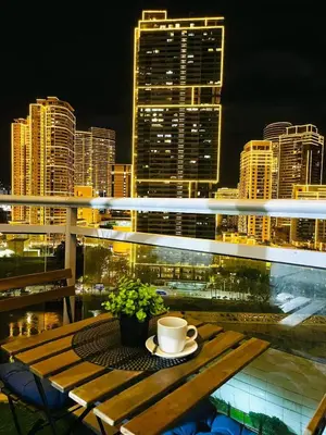a cup of coffee on a table on a balcony with a city skyline at 1BR Acqua Residences ,Mandaluyong just 3-5 mins to Makati district in Manila