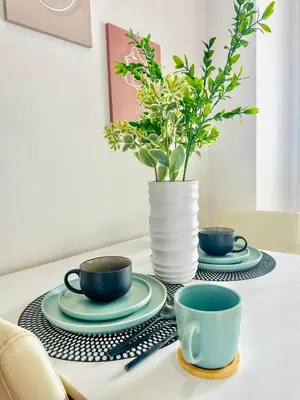 a table with two cups and a vase with a plant at 1BR Acqua Residences ,Mandaluyong just 3-5 mins to Makati district in Manila