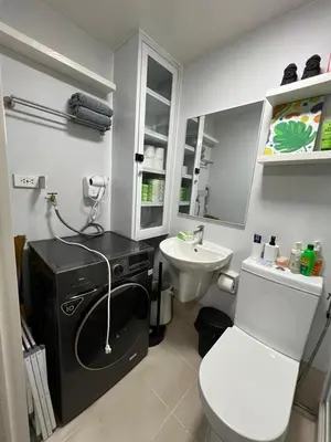 a bathroom with a white toilet and a sink at Fullerton Suites in Silang