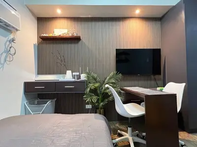a bedroom with a bed and a desk and a tv at Fullerton Suites in Silang