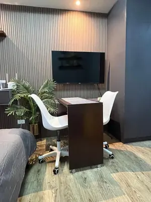 a bedroom with a desk with a computer and two chairs at Fullerton Suites in Silang