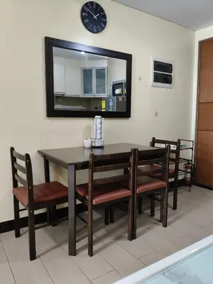 a dining room table with chairs and a clock on the wall at LDN 5J - Condotel Newport in Manila