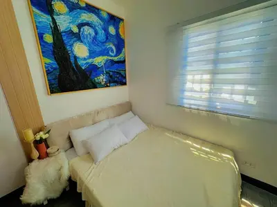 a bed in a room with a painting on the wall at Elyana's Staycation in Pasalada