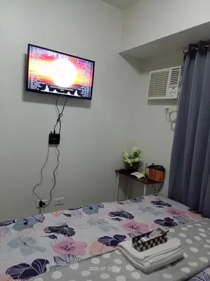 a bedroom with a bed with a tv on the wall at Nics Condotel - Mandaluyong Along Edsa in Manila