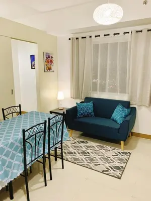 a living room with a blue couch and a bed at 2br condo in Southmall Las Pinas 25 mins to NAIA - 709T3 in Manila