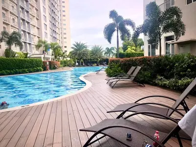 a swimming pool with chairs and palm trees and buildings at 2br condo in Southmall Las Pinas 25 mins to NAIA - 709T3 in Manila