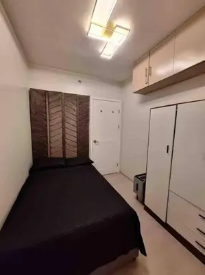 a bedroom with a black bed and a white refrigerator at 2-Bedroom Condo with Swimming Pool in Manila