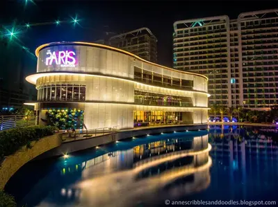 a building with a reflection in the water at night at 1BR Condotel at Azure Urban Resort Near Airport #AZ06 in Manila