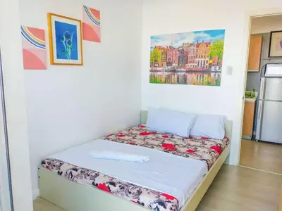 a bed in a room with a painting on the wall at Cozy 2 Bedroom With Blacony in Manila