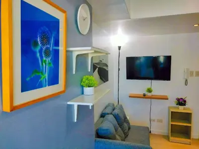 a living room with a couch and a flat screen tv at Cozy 2 Bedroom With Blacony in Manila