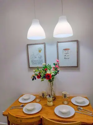 a wooden table with plates and a vase of flowers at Cozy 2 Bedroom With Blacony in Manila