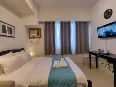 a hotel room with a bed and a desk and a television at 1BR Condotel Ridgewood Towers Taguig City #RW15 in Manila