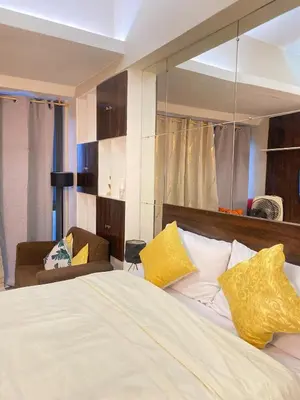 a bedroom with a large bed with yellow pillows at Stylish and relaxing studio unit in Manila
