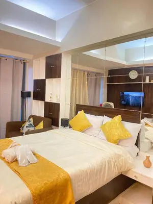 a bedroom with a large white bed with yellow pillows at Stylish and relaxing studio unit in Manila