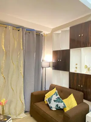 a living room with a brown couch and curtains at Stylish and relaxing studio unit in Manila