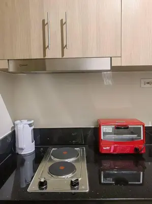 a red toaster sitting on top of a stove in a kitchen at 1BR Condotel with Balcony at FAME Residences #FM37 in Manila