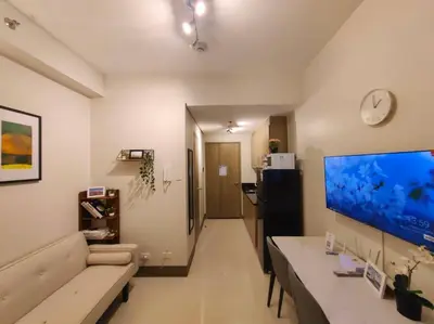 a living room with a couch and a large screen tv at 1BR Condotel with Balcony at FAME Residences #FM51 in Manila