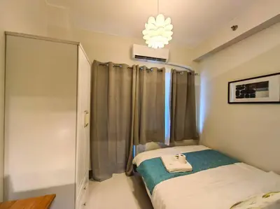 a small bedroom with a bed and a chandelier at 1BR Condotel with Balcony at FAME Residences #FM52 in Manila