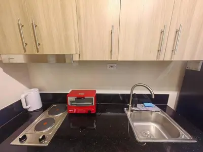 a kitchen counter with a sink and a red appliance at 1BR Condotel with Balcony at FAME Residences #FM52 in Manila