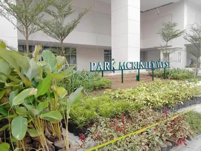 a sign in front of a building with plants at Park Mckinley West 1BR in Manila