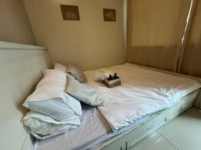 a bed with white sheets and a box of pillows at Cozy 1 Bedroom Makati Condo with Balcony Wifi in Manila