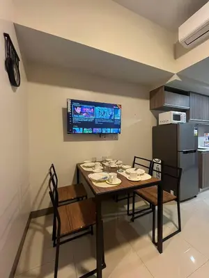 a dining room with a table and chairs and a refrigerator at Park McKinley West unit 9Y Tower B in Manila