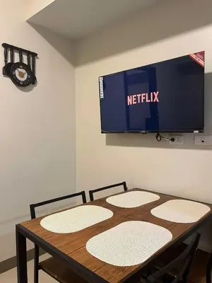 a table with two chairs and a television on a wall at Park McKinley West unit 9Y Tower B in Manila