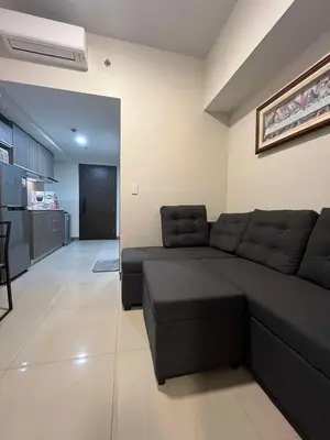 a living room with a black couch and a kitchen at Park McKinley West unit 9Y Tower B in Manila