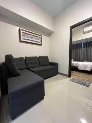 a living room with a black couch and a mirror at Park McKinley West unit 9Y Tower B in Manila