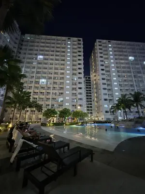 a large swimming pool in a city at night at Industrial Design Bachelor's Pad with Pool View in Shore Residences in Manila
