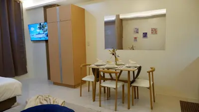 a room with a table and chairs and a refrigerator at New Cozy Condo in Eastwood in Manila