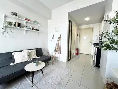 a living room with a black couch and a table at Vibrant Makati Studio in Manila