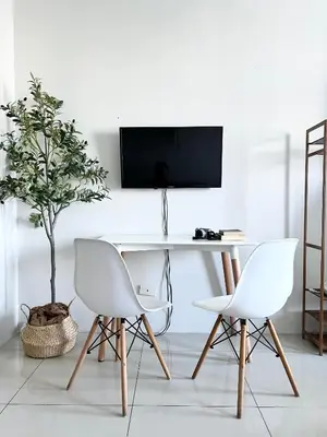 a white desk with two chairs and a tv on a wall at Vibrant Makati Studio in Manila