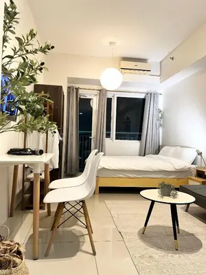 a bedroom with a bed and a table and a chair at Vibrant Makati Studio in Manila