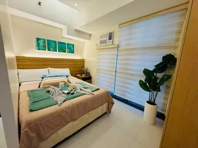 a bedroom with a bed and a plant and a window at Staycation in Mckinley walking distance to Venice Mall in Manila
