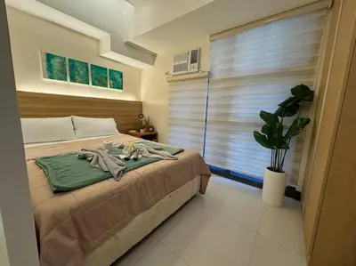 a bedroom with a bed and a large window at Staycation in Mckinley walking distance to Venice Mall in Manila
