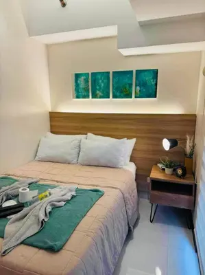 a bedroom with a bed and a wooden head board at Staycation in Mckinley walking distance to Venice Mall in Manila