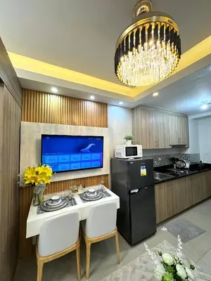 a kitchen with a white table and a black refrigerator at Gray Room Shore 2 Residences in Manila