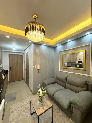 a living room with a couch and a chandelier at Gray Room Shore 2 Residences in Manila