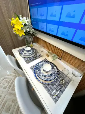 a table with plates and glasses and a computer monitor at Gray Room Shore 2 Residences in Manila