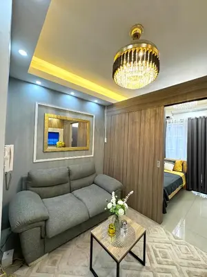 a living room with a couch and a chandelier at Gray Room Shore 2 Residences in Manila