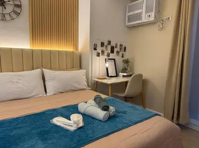 a bedroom with a bed with towels and a desk at Staycation in venice residences Mckinley with balcony in Manila