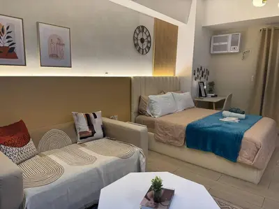 a hotel room with two beds and a couch at Staycation in venice residences Mckinley with balcony in Manila