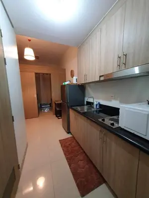 a kitchen with wooden cabinets and a white microwave at Shore 2 Residences Tuscia Home Staycation in Manila