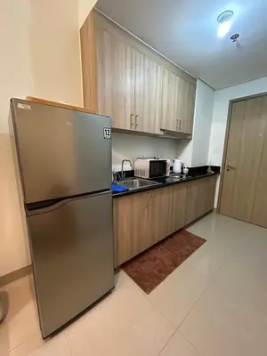 a kitchen with a stainless steel refrigerator and wooden cabinets at Shore 2 Residences Tuscia Home Staycation in Manila