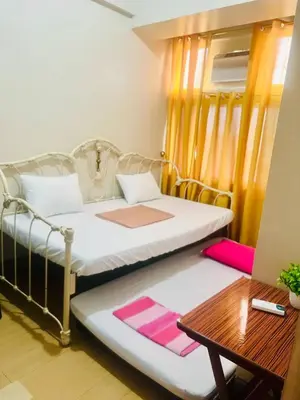 two beds in a small room with a table at 2 Bedroom condo unit in Manila