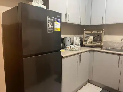 a kitchen with a stainless steel refrigerator and white cabinets at 2 Bedroom condo unit in Manila