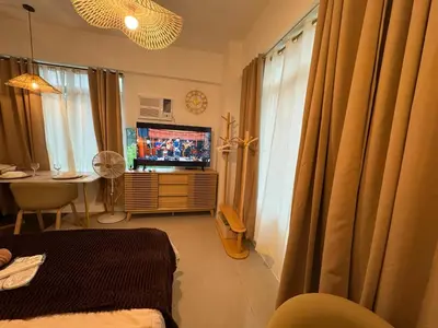 a living room with a tv and a desk with a desk at Budget Friendly Staycation walking distance to Venice Mall with Netflix and Wifi in Manila