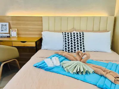 a bed with a blue blanket and towels on it at Budget Friendly Staycation walking distance to Venice Mall with Netflix and Wifi in Manila